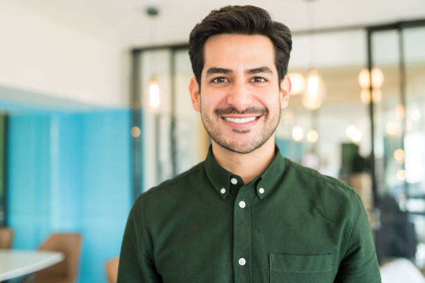 Portrait of smiling Latin businessman standing at office